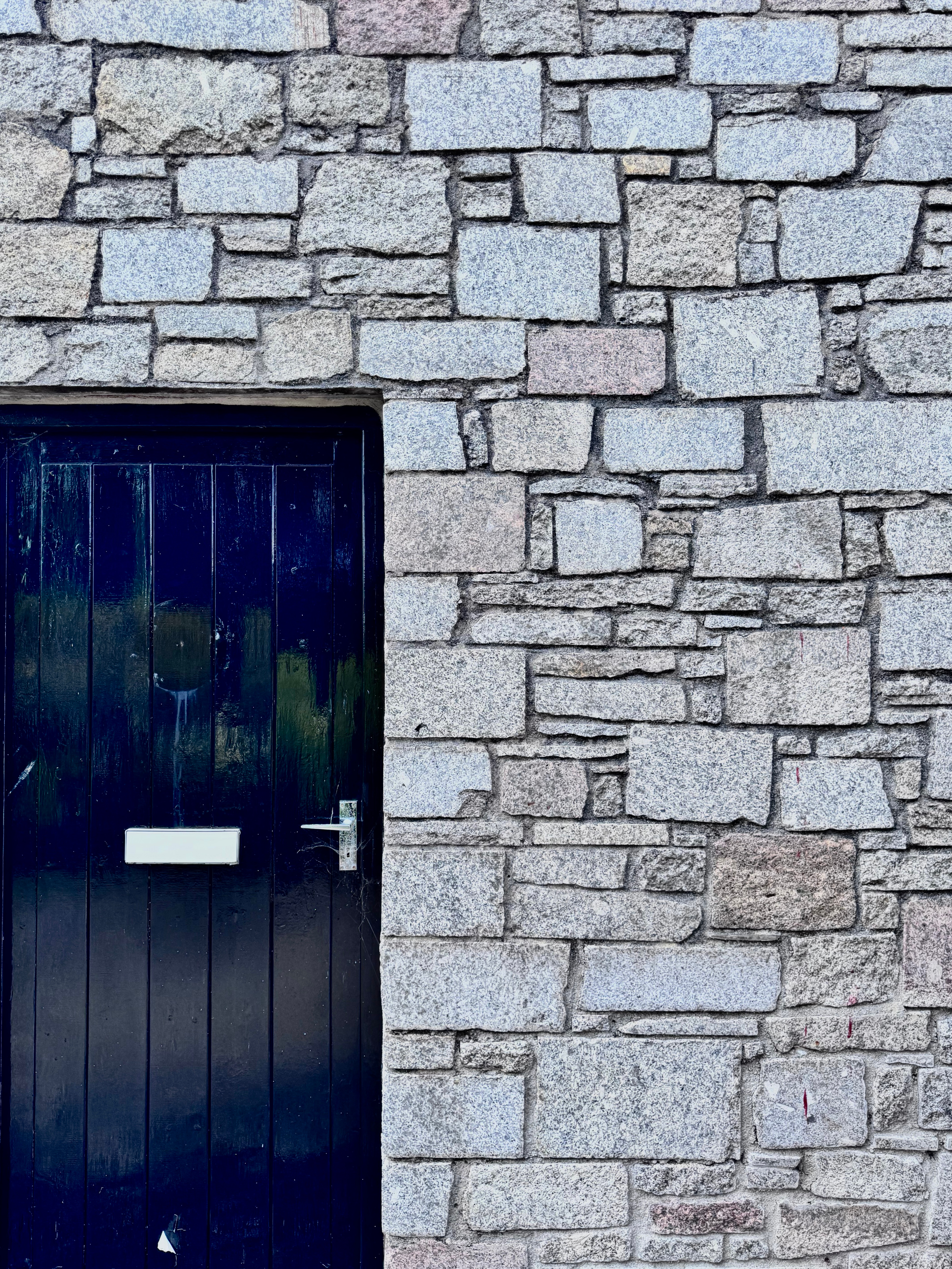 A dark blue painted door in a granite rubble-stone wall.