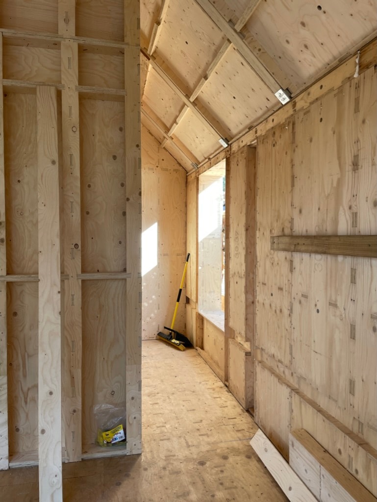 A vaulted roof room built from a CNC-cut plywood frame, with a window opening letting sunlight pour in.